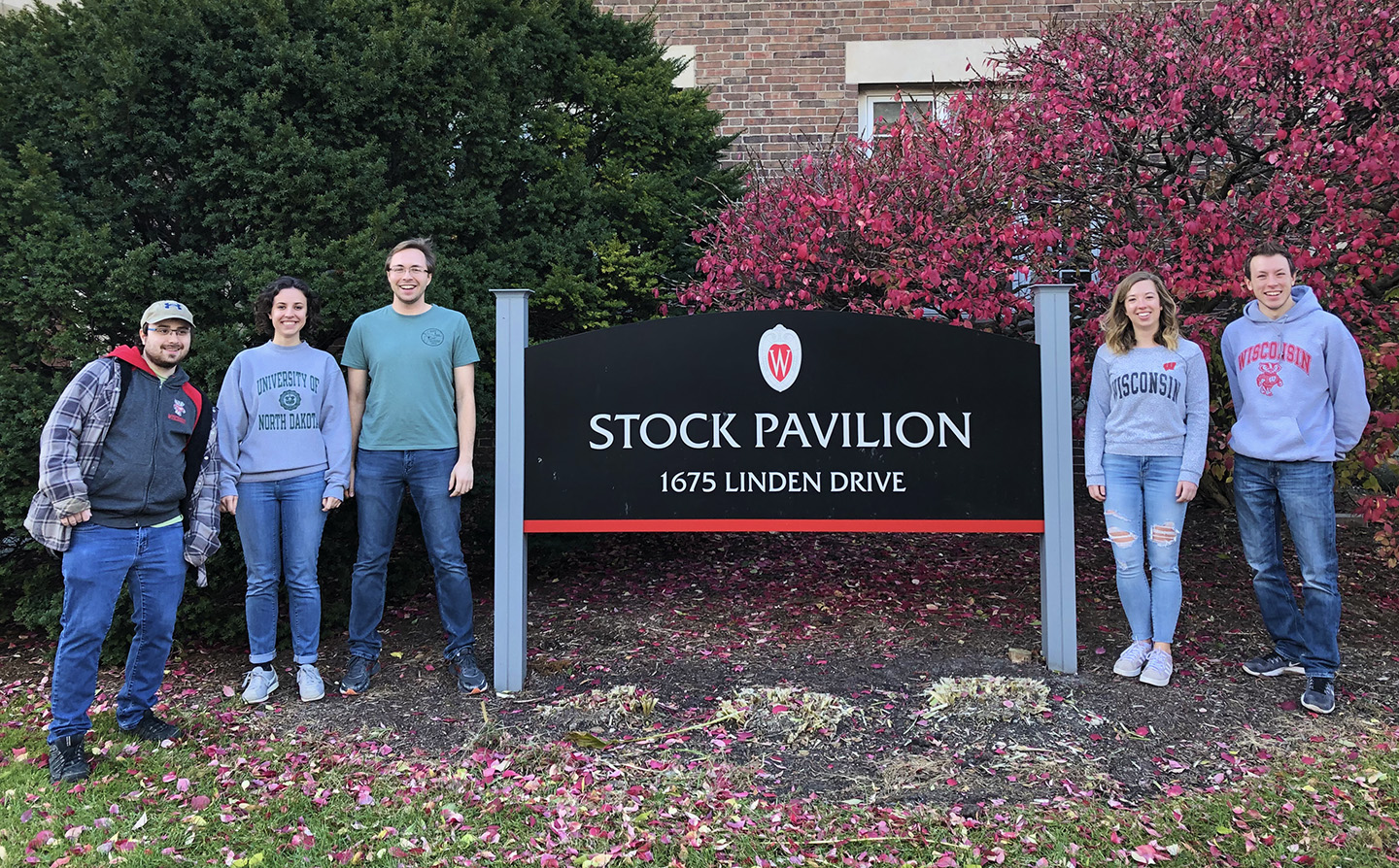 Five students standing next to the UW Stock Pavilion sign.